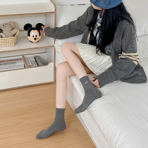 Detail of gray ribbed knit crew socks featuring small white Hi heart embroidery on the side