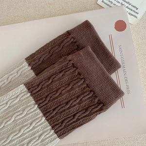 Detail of cable knit leg warmers in two-tone brown and beige with textured stitch