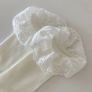 Detail of cream white knit socks with intricate double-layered floral lace trim and ribbing