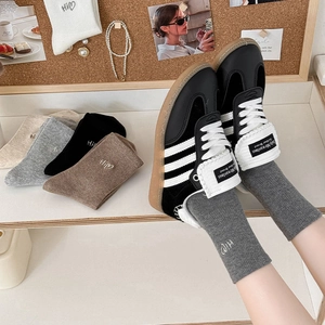 Close-up of crew socks with heart embroidery next to vintage-style leather sneakers