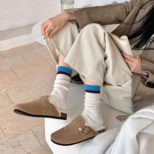 Gros plan de sabots en daim marron avec doublure peluche et chaussettes en laine