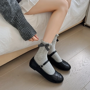 Close-up of gray cotton socks with lace edges and a polka dot bow with Mary Janes