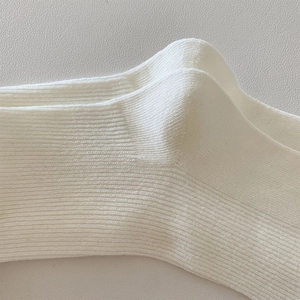 Macro detail of white cotton ribbed knit socks with soft texture and durable heel construction