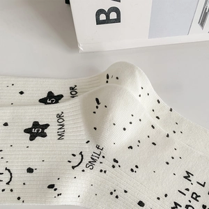 Close-up of white ribbed knit socks featuring black star, smiley face and text prints