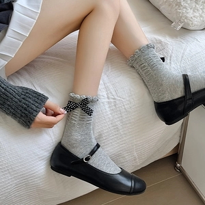 Detail of grey ruffled socks with black polka dot bow paired with Mary Jane shoes