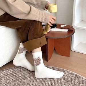 Détail de chaussettes blanches en coton avec broderie animale marron sur le côté