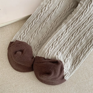 Detailed close-up of retro cable-knit socks featuring contrast heel and toe patch texture