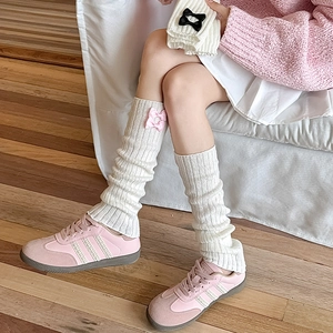Détail de jambières en tricot avec des nœuds roses et une texture crème douce