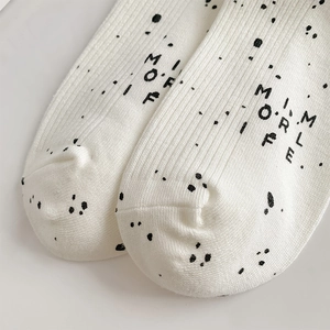 Detail of white ribbed knit socks featuring black polka dots and stylish typography