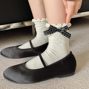 Detail of white ruffle socks with black polka dot bow paired with Mary Jane shoes
