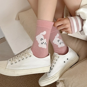 Détail de chaussettes roses avec broderie de chat blanc et baskets en toile