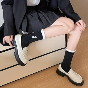 Detail of black crew socks with white bow embroidery styled with platform loafers