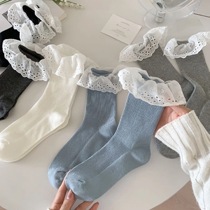 Detail of delicate layered lace ruffles and floral embroidery on ribbed cotton socks