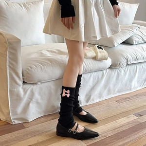 Détail de jambières noires en maille avec nœuds roses pour le style Lolita et JK