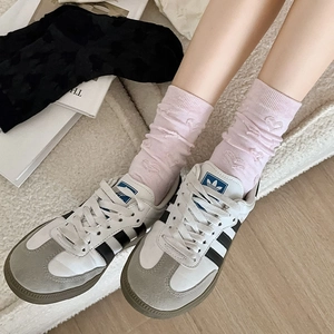 Detail of pink crew socks with embossed heart patterns paired with white sneakers
