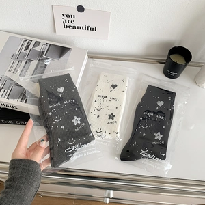 Detailed close-up of knit crew socks in grey, white, and black with starry graffiti patterns