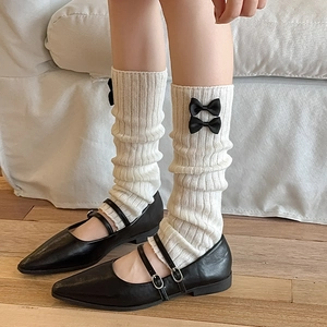 Détail de jambières en tricot blanc avec nœuds noirs et chaussures Mary Jane