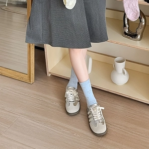 Detail of cream sneakers with silver stripes and light blue heart patterned crew socks