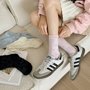 Detail of pink heart-embossed socks with ribbed cuffs on lifestyle sheepskin background