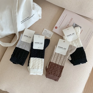 Detail of color-block cable knit socks in diverse colors on a cozy fabric background
