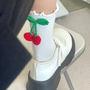 Détail de chaussettes blanches à volants avec breloques cerises 3D et chaussures Mary Jane