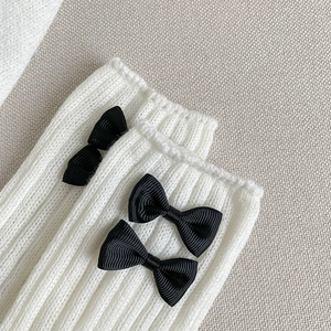 Gros plan sur des jambières en maille blanche avec nœuds noirs pour un style d'hiver