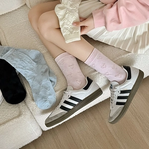 Detail showing heart-patterned mid-calf socks in pink, blue, black and beige colors
