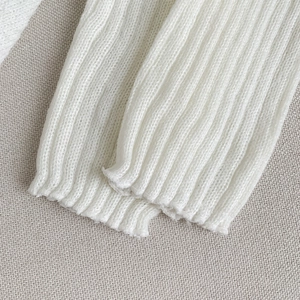 Gros plan détaillé sur les jambières blanches en maille côtelée avec texture verticale