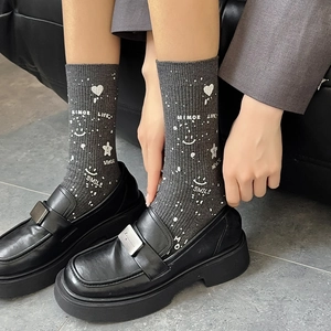 Detail of grey crew socks with smile and heart patterns worn with black loafers