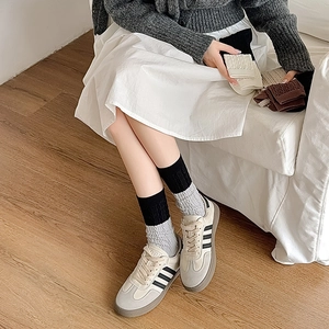 Detailed view of women's cable knit crew socks in neutral tones and ribbed texture