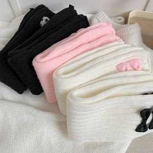 Détail de jambières en tricot montrant la texture côtelée et les nœuds en ruban en trois couleurs