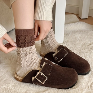 Close-up of retro cable knit socks with brown trim paired with plush suede mule slippers