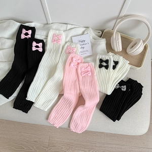 Détail de jambières en maille côtelée avec de délicats nœuds en rose, blanc et noir