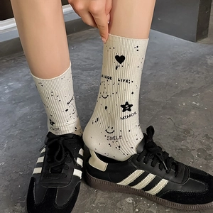 Close-up of cream crew socks with black graffiti print, star patterns and smile text