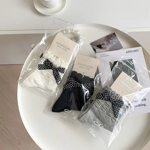 Three-pair lace-edge sock set in white, black, and grey with bow details in retail packing