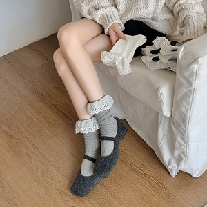 Detail of grey knitted mid-calf socks with white lace trim and Mary Jane flat shoes