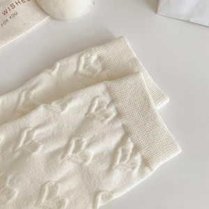 Detailed view of cream white knitted socks featuring a raised textured 3D heart pattern