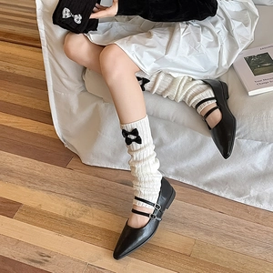 Détail de jambières blanches avec nœuds noirs et chaussures Mary Jane