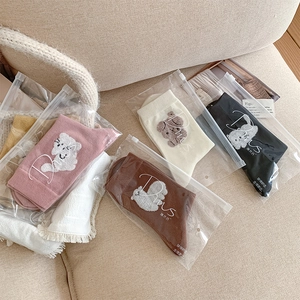 Détail de chaussettes à broderies animaux dans un sac d'emballage givré à zip