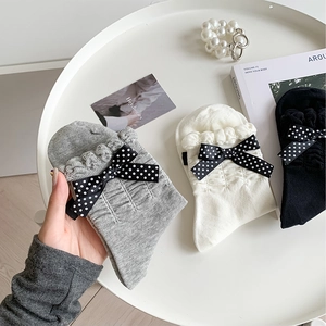 Close-up of sweet lace trim socks with polka dot bows in grey, white, and black colors
