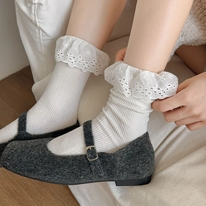 Detail of white ribbed crew socks with hollow lace trim and grey Mary Jane shoes
