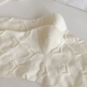 Detail of cream white knit sock with embossed heart pattern and fine stitching texture