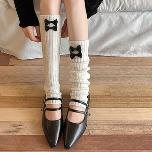 Détail de jambières en tricot blanc côtelé avec de jolis nœuds en satin noir décoratifs