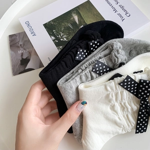 Close-up of knit socks with polka dot bows and delicate lace trim in black and grey