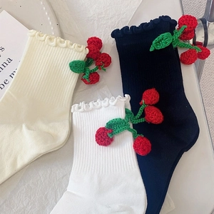 Détail de chaussettes à bord volanté avec décorations de cerises au crochet faites à la main