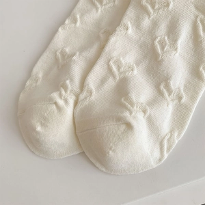 Macro shot of cream knit socks featuring 3D embossed heart patterns and soft texture