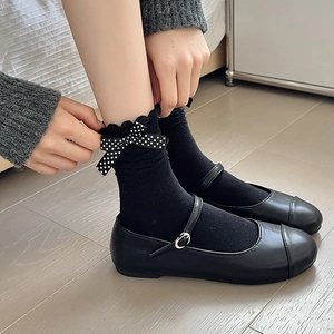 Detail of black cotton socks with lace cuffs and white polka dot bow decoration
