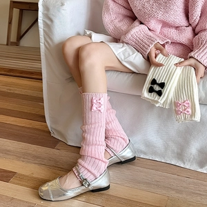 Détail de jambières en tricot rose et blanc avec nœuds et rayures verticales douces