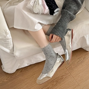 Close-up of silver leather ballet flats with grey lace polka dot socks for women