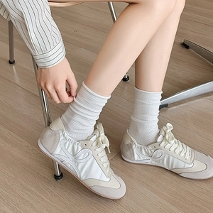 Baskets rétro en daim beige et blanc portées avec des chaussettes en maille blanches